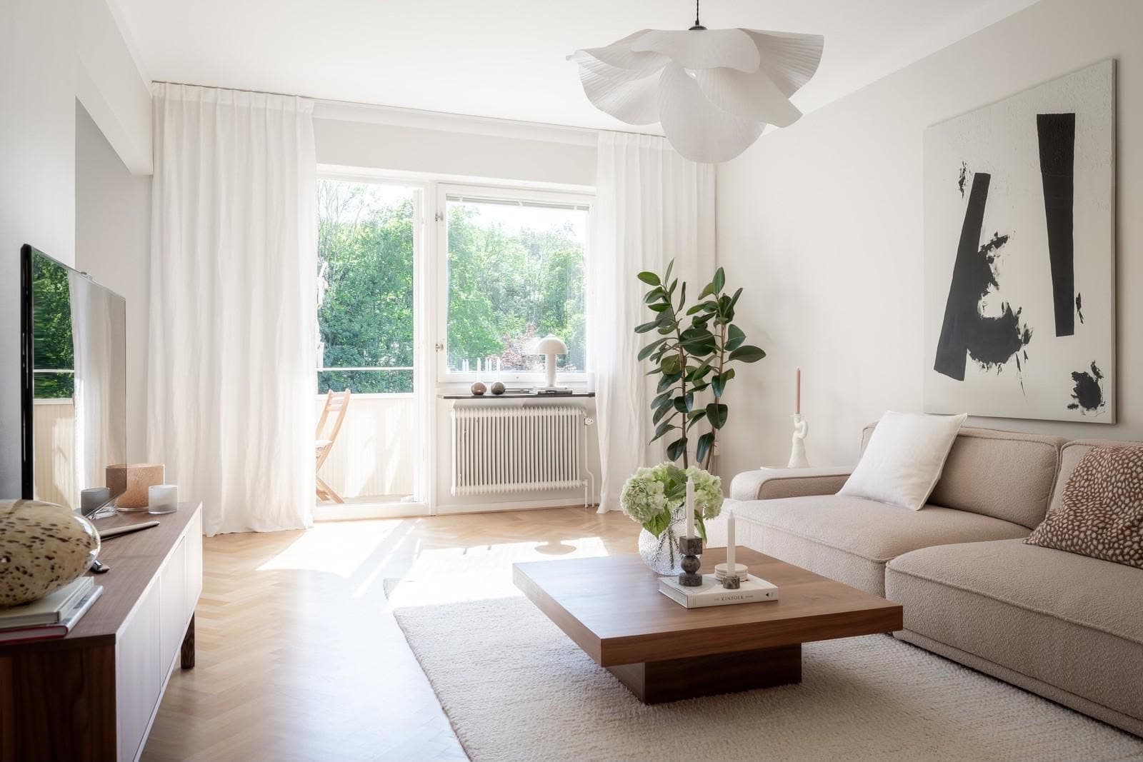 Ljust vardagsrum med soffa och stora fönster efter städning.